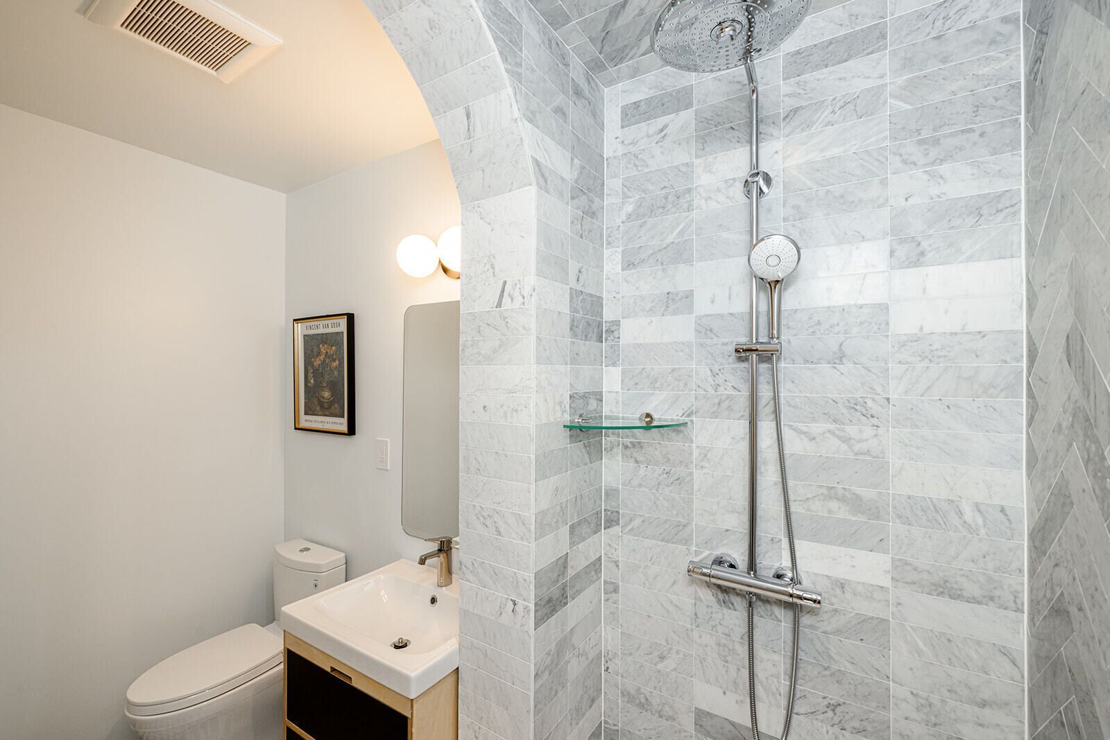 Ein Badezimmer mit Dusche, Toilette, Waschbecken und Spiegel.