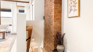 A modern interior with exposed brick, wooden beams, and a staircase leading to an upper level.