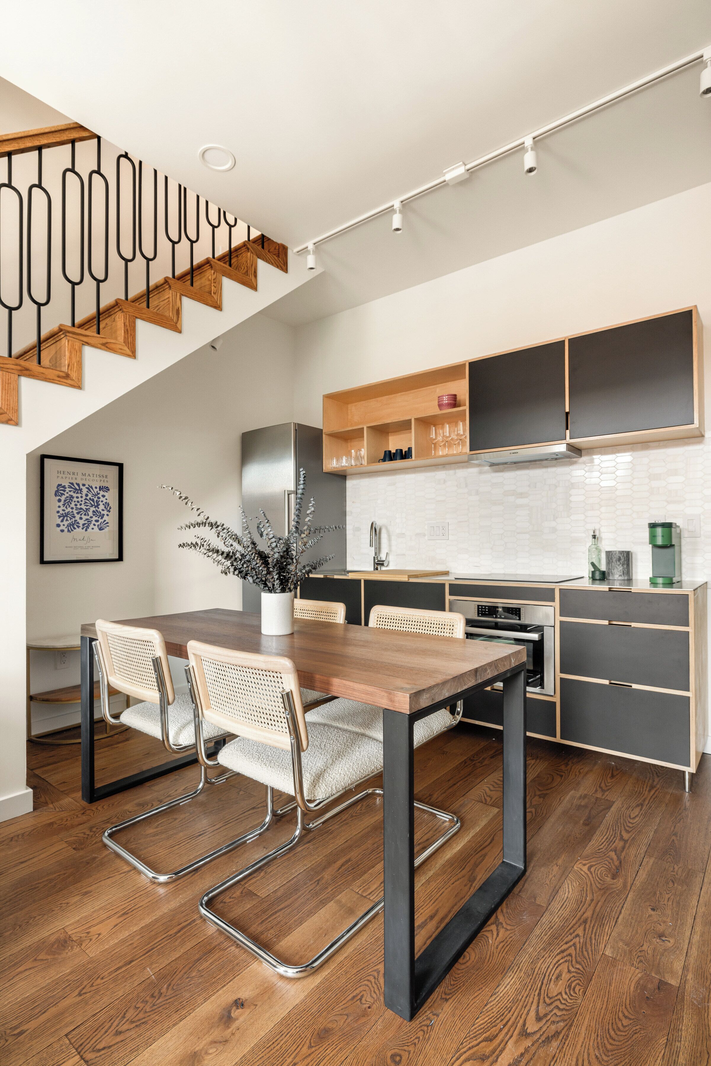 Een moderne keuken met een houten trap, inbouwmeubels en een eethoek met een houten tafel en stoelen.