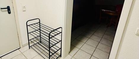 A hallway with a metal rack, a door, and a tiled floor.