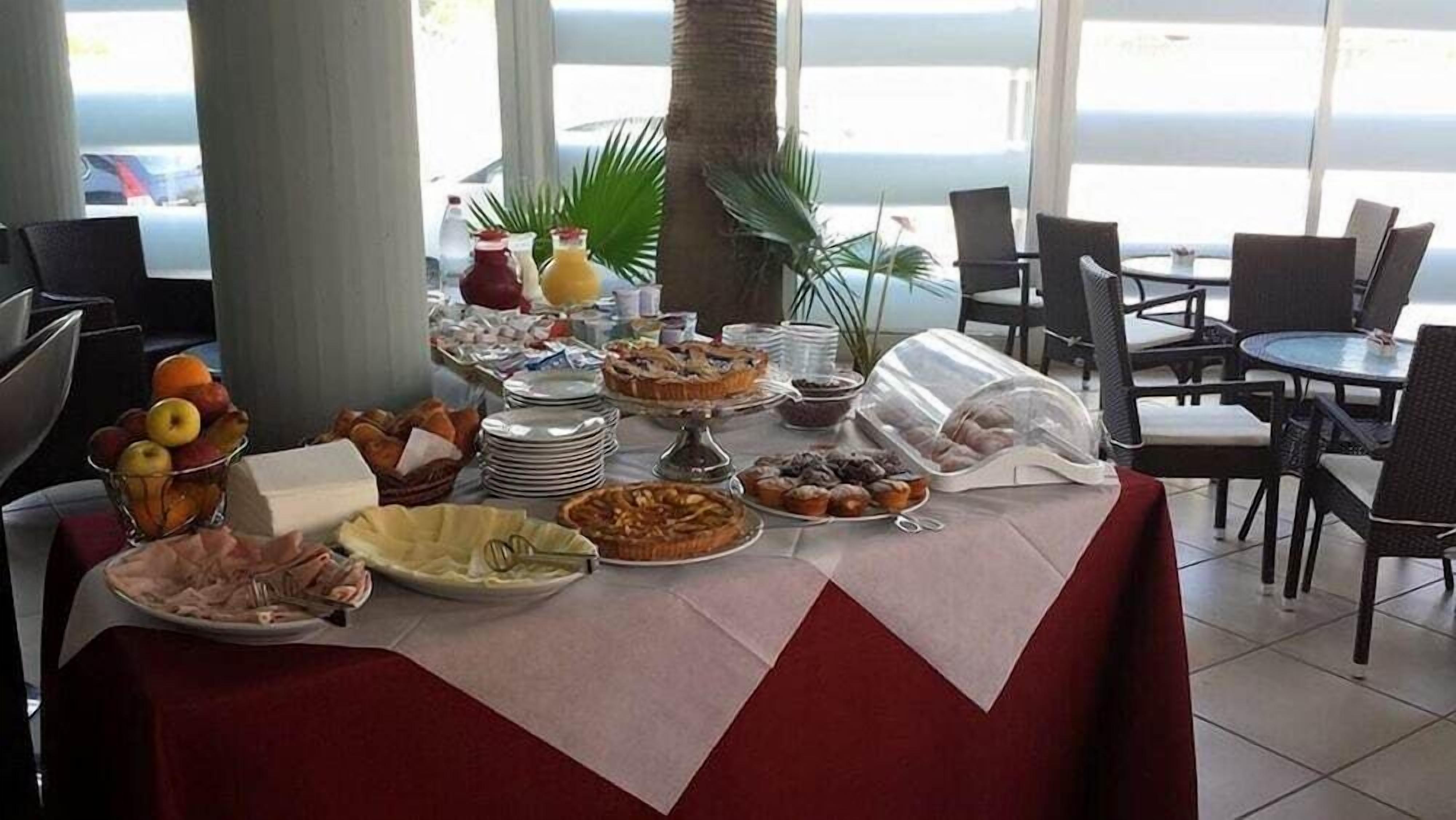 Ein Buffet mit verschiedenen Speisen, Tellern und einem durchsichtigen Kunststoffbehälter.