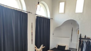 Een kamer met een eettafel, stoelen, een bed, een bijzettafeltje en een garderobe.