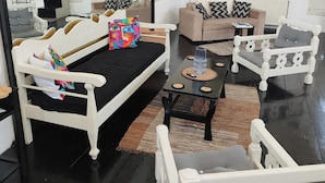 Een moderne woonkamer met een bank, fauteuils, een salontafel en een grote spiegel.