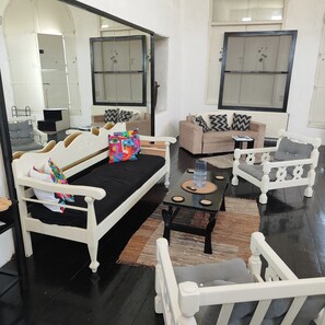 A modern living room with a sofa, armchairs, a coffee table, and a large mirror. - Charming Holiday House in Mikonos With Garden View (Mykonos)