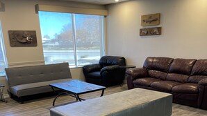 A living room with a grey sofa, a brown leather couch, a small table, and a large ottoman.