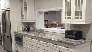 A kitchen with white cabinetry, a stainless steel refrigerator, a microwave, and a built-in oven.