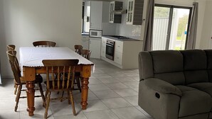 Una cocina moderna con armarios blancos, una mesa de comedor con sillas de madera y un sofá gris.