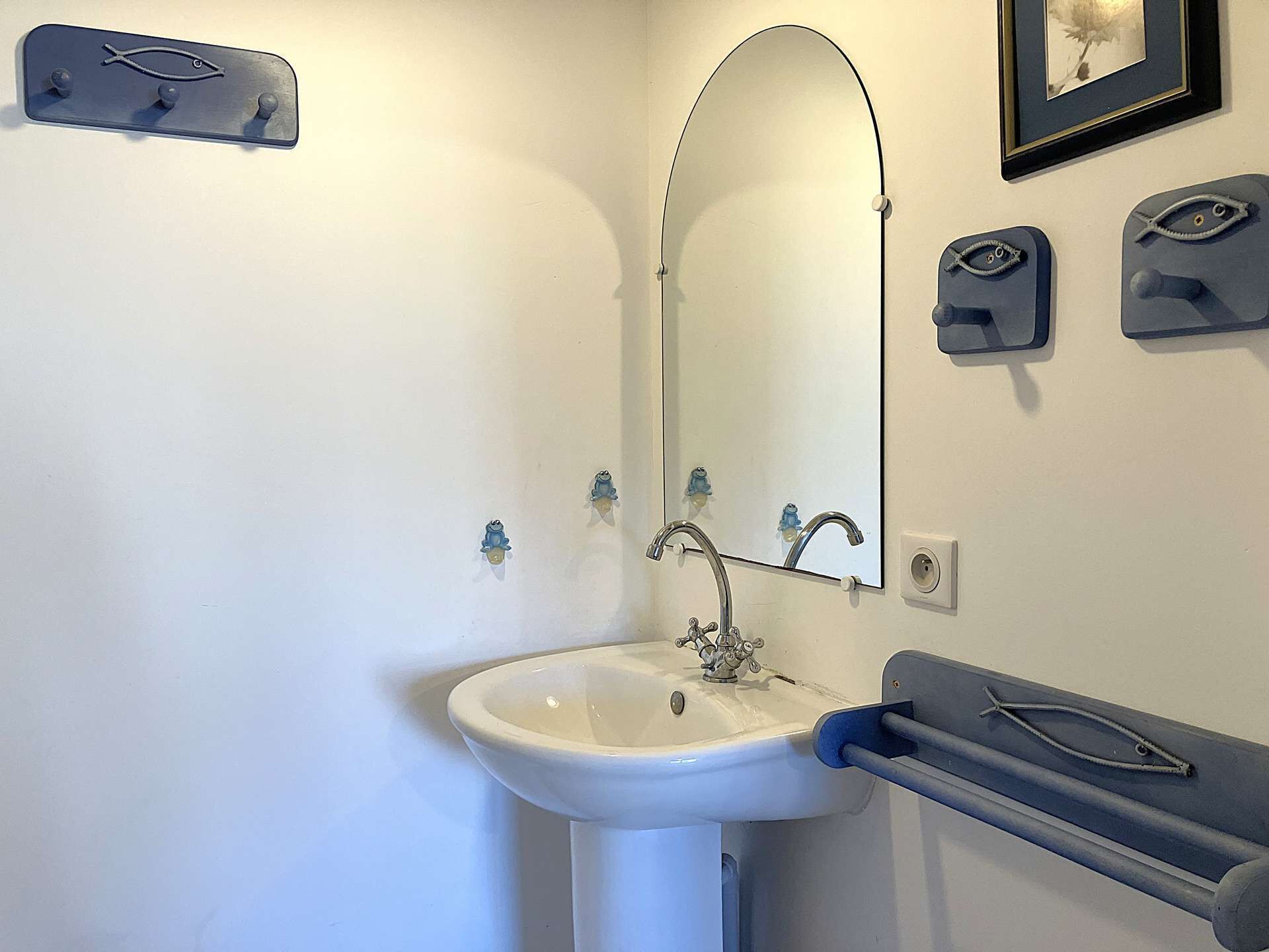A bathroom with a sink, mirror, towel rack, and a framed picture on the wall.