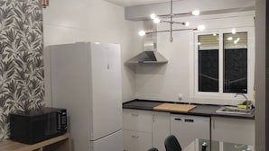 A modern kitchen with a refrigerator, microwave, and dining table with chairs. - Charming Ground Floor Apartment With Sea Views in Bueu (Bueu)