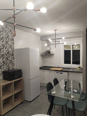 Eine moderne Küche mit Kühlschrank, Mikrowelle und Esstisch mit Stühlen.