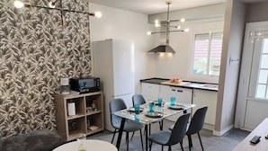 A modern kitchen with white cabinets, a dining table with chairs, a microwave, and a coffee maker on a shelf. - Charming Ground Floor Apartment With Sea Views in Bueu (Bueu)