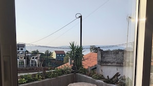 A balcony with a stone table, a potted plant, and a view of buildings and a mountain in the background. - Charming Ground Floor Apartment With Sea Views in Bueu (Bueu)