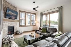 A living room with a fireplace, a sofa, a coffee table, and a dog. - Downtown WP Condo F-202 I Private Hot Tub I Great Views I Bunk Room I Discounted Attractions (Fraser)