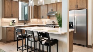 Una cucina moderna con mobili in legno, un frigorifero in acciaio inossidabile e luci a sospensione.