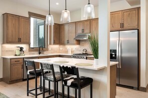 A modern kitchen with wooden cabinets, a stainless steel refrigerator, and pendant lighting. - Downtown WP Condo F-202 I Private Hot Tub I Great Views I Bunk Room I Discounted Attractions (Fraser)