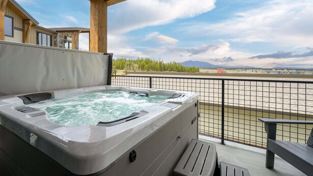 Una vasca idromassaggio su un balcone con vista su un fiume e montagne.