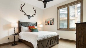 Una camera da letto con un letto, una ventola a soffitto, una finestra e opere d'arte alle pareti.