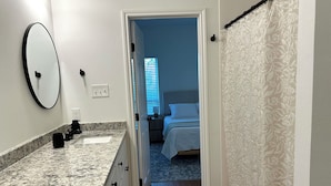 Un baño con encimera de granito, espejo y lavamanos.