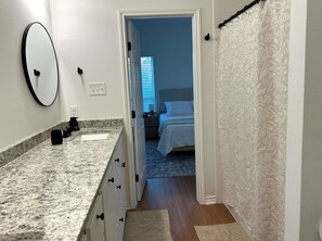 Ein Badezimmer mit Granitplatte, Spiegel und Waschbecken.
