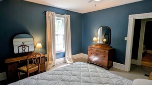 A bedroom with a bed, a desk, a dresser, a ceiling fan, and a window with curtains. - Gaspereau Heritage House - Annapolis Valley (Wolfville)