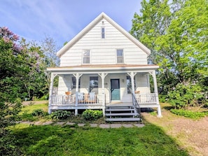 A white two-story house with a porch, number 29, surrounded by greenery.