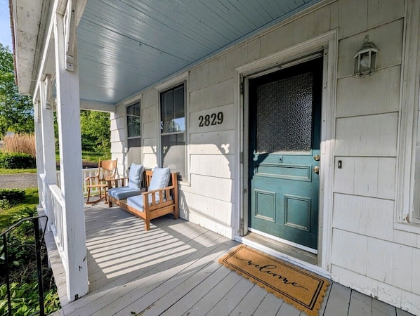 A porch with a number '2829' on the wall, a green door, and a welcome mat.