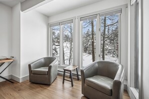 A modern room with two leather chairs, a small wooden table, and large windows with a snowy view. - 4 O'Clock Lodge D27: Remodeled condo close to town and the slopes - New Listing. (Breckenridge)