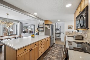 A modern kitchen with a large island, wooden cabinets, stainless steel appliances, and a view to the outside. - 4 O'Clock Lodge D27: Remodeled condo close to town and the slopes - New Listing. (Breckenridge)
