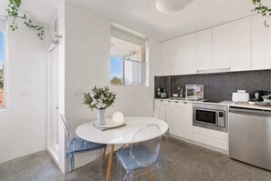 A modern kitchen with white cabinets, a black and white backsplash, and stainless steel appliances. - Rooftop-Pool Studio Stay in Bondi (Bondi)