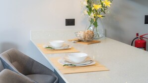 Una cocina moderna con una encimera larga, un jarrón con flores amarillas y un extintor.
