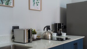 Una cocina con tostadora, hervidor, cafetera y fregadero.