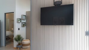 Una sala de estar moderna con un televisor de pantalla plana montado, una planta en maceta y un diseño minimalista.