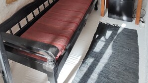 A small, rustic room with a single bed, a small table with a kettle, and a refrigerator. - Room-charming Studio Rental in Mikonos w (Mykonos)
