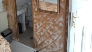 A bathroom with a white sink, a mirror, and a door. - Room-charming Studio Rental in Mikonos w (Mykonos)