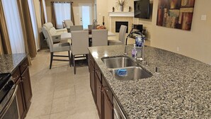 A kitchen with granite countertops, a built-in oven, and a dining area with chairs and a table. - Peaceful Retreat for Travel Nurses & Corporate Stays (Spring)
