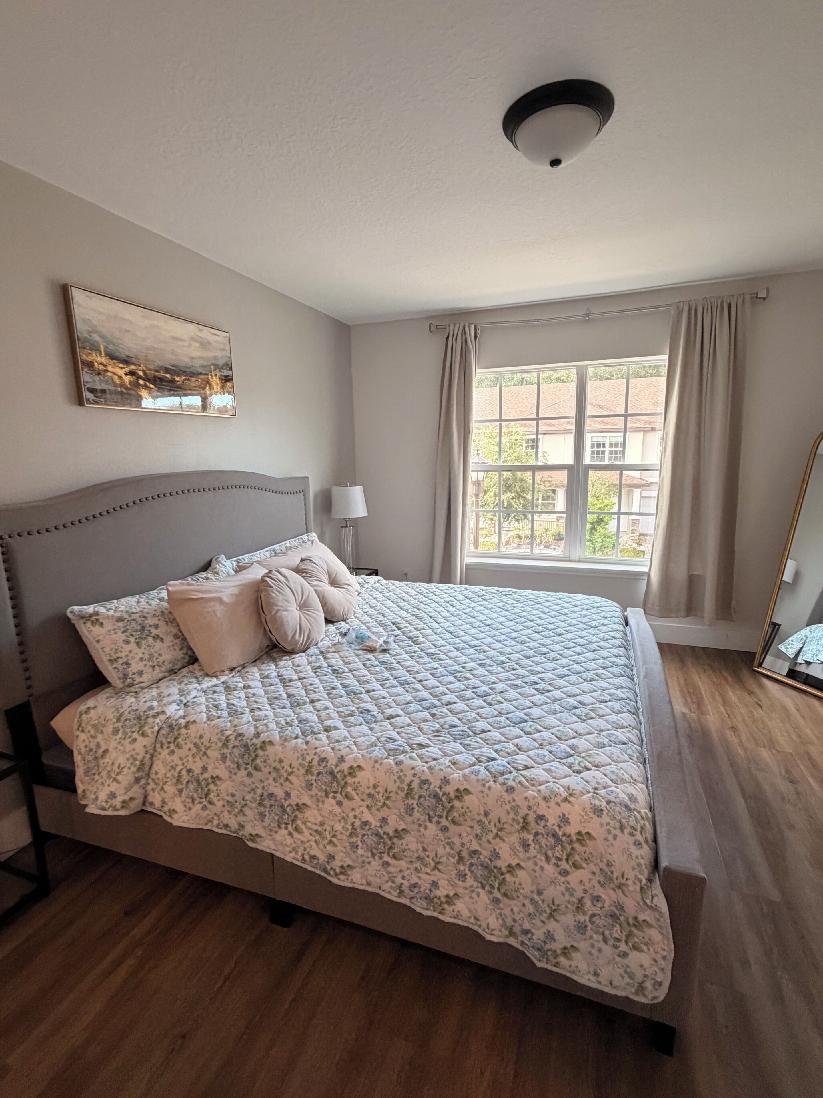 Une chambre à coucher avec un lit, une fenêtre, une lampe et un luminaire au plafond.