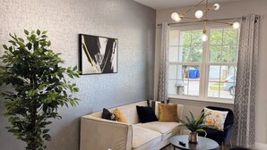 A modern living room with a sofa, black armchair, round coffee table, and a potted plant. - Super Calm-Sleeps 13 w Designs & close to Parks! (Kissimmee)