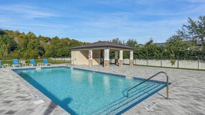 A rectangular swimming pool with a tiled deck, a covered pavilion, and blue lounge chairs. - Super Calm-Sleeps 13 w Designs & close to Parks! (Kissimmee)