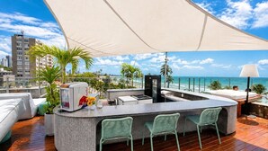 A rooftop bar with a stone counter, seating area, and a view of the ocean. - Setai Garden Yatch  (João Pessoa)