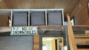 Un interior de madera con un cartel que dice 'NO SNOWMOBILES' y una pared de azulejos.