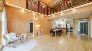 A spacious living area with a dining table, a rocking chair, and a kitchen in the background. - Gangneung Stay Gaju Gangneung (Gangneung)
