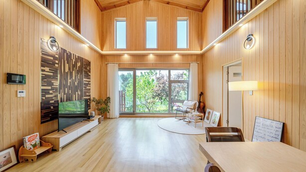 A spacious room with wooden walls, a large window, a flat-screen TV, a dining table, and a violin. - Gangneung Stay Gaju Gangneung (Gangneung)