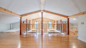 A spacious attic room with wooden beams, a mezzanine level, and a large window. - Gangneung Stay Gaju Gangneung (Gangneung)