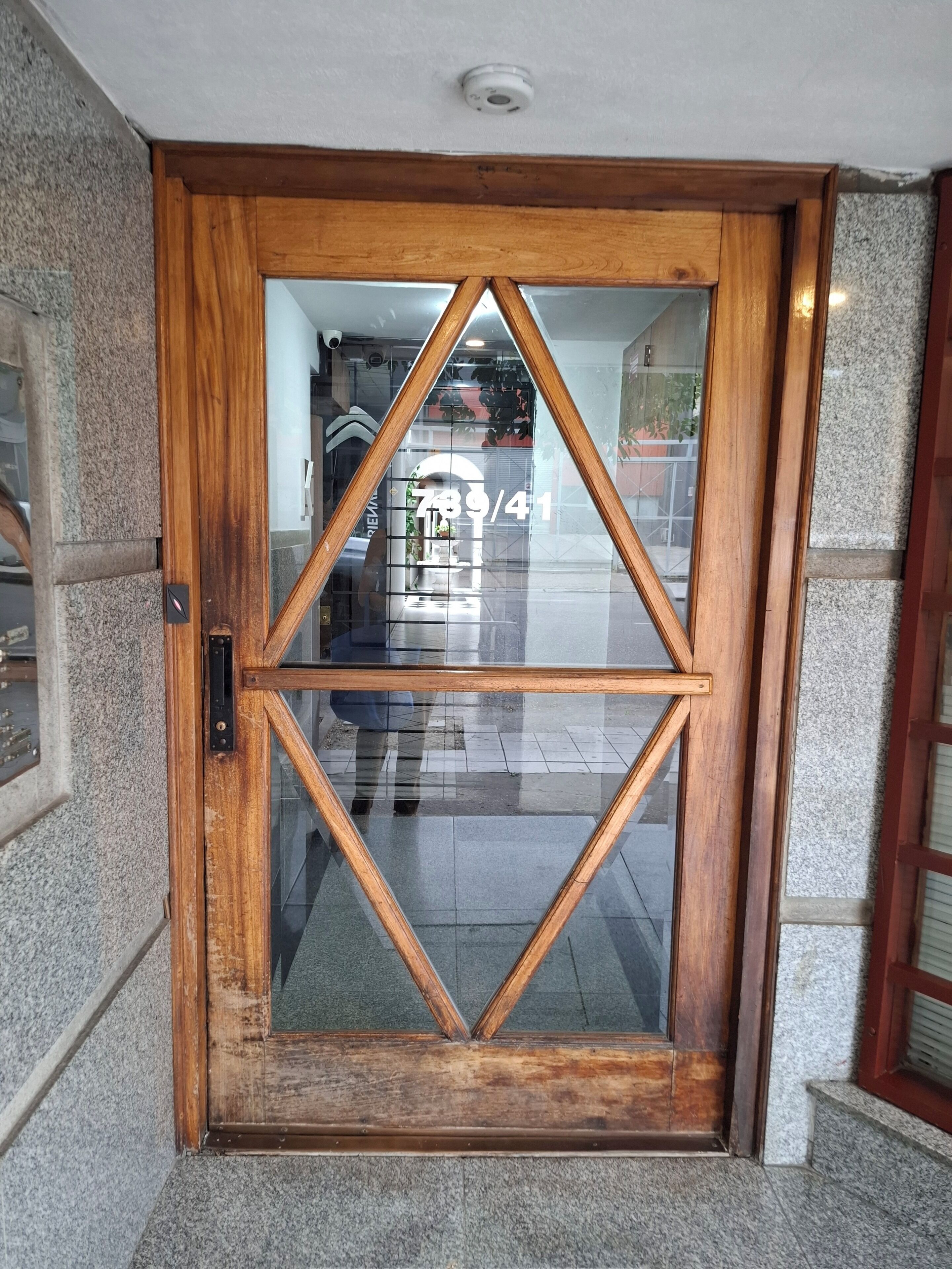 A wooden door with a geometric glass panel design.