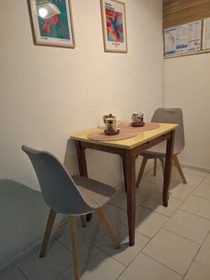 A dining table with two chairs, a framed artwork on the wall, and a bulletin board with papers.