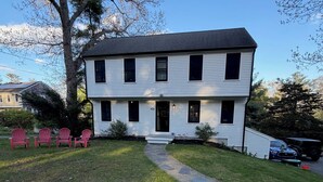A two-story house with a paved driveway, a tree, and a row of red chairs. - Short drive to local beaches. Levitate Festival’s less than a mile and walkable  (Marshfield)
