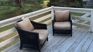 A wooden deck with two wicker chairs and a white railing. - Short drive to local beaches. Levitate Festival’s less than a mile and walkable  (Marshfield)