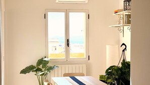 A compact kitchen with a dining area, a potted plant, and a view through a window.