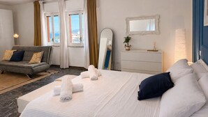 A hotel room with a bed, a sofa, a dresser, and a mirror.