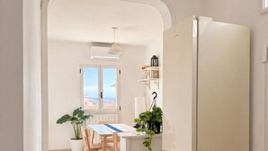 A kitchen with a white refrigerator, a dining table with chairs, a potted plant, and a window with a view.